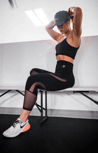Woman in gym wear sitting on a bench in a gym